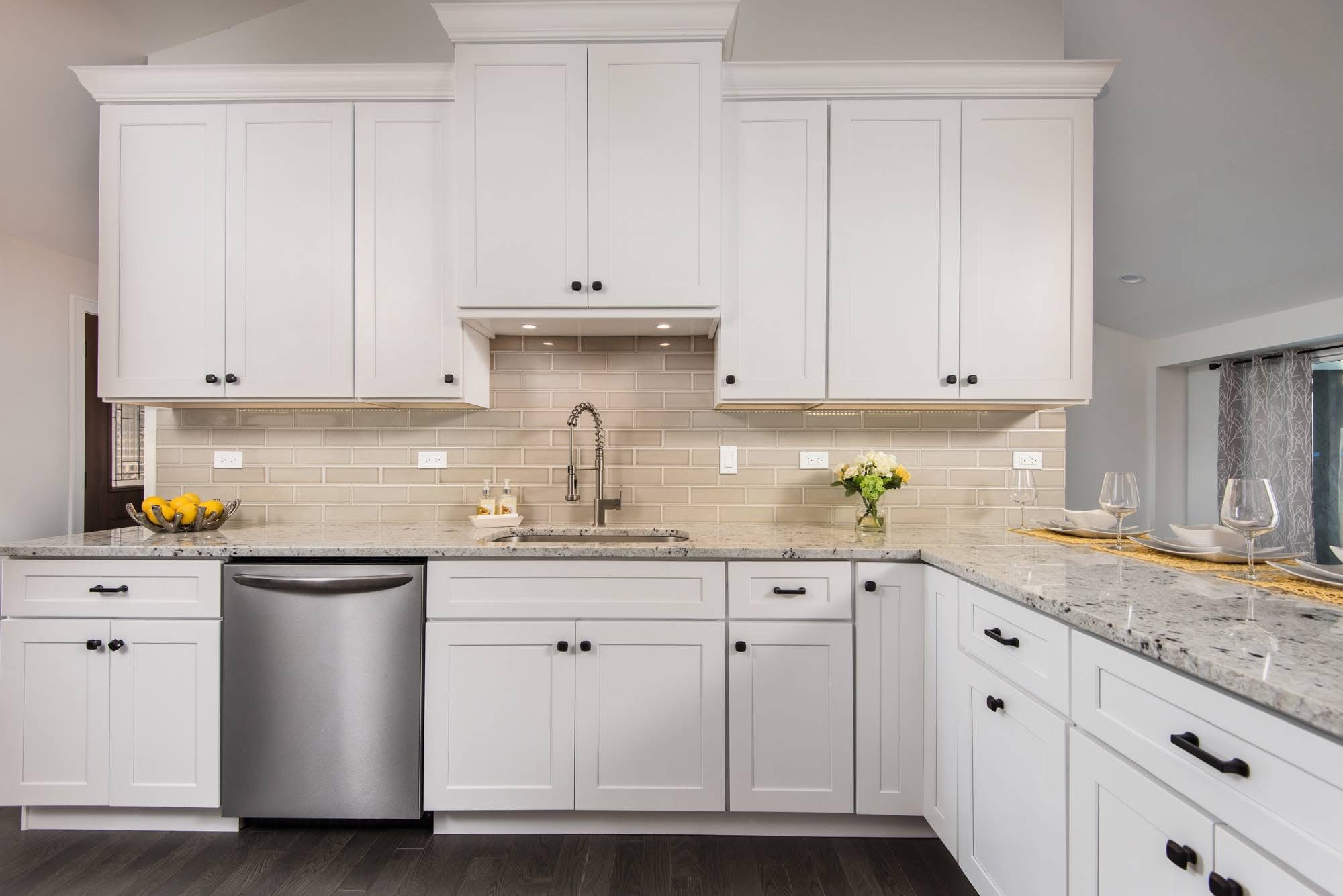 Bright white kitchen with granite counters and shaker cabinets