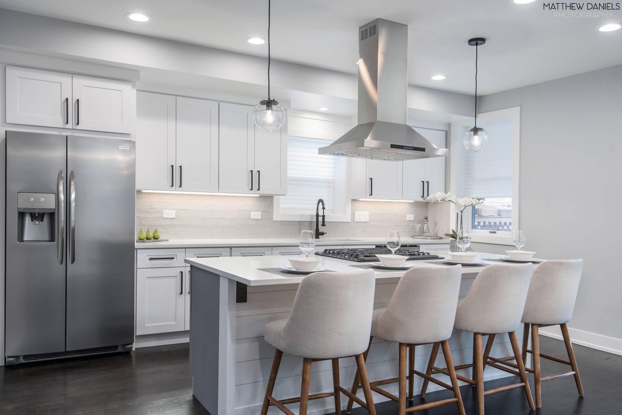 White kitchen remodel with island and stainless hood